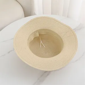 Detail view of beige flat-top straw sun hat with inner adjustable band for summer beach.