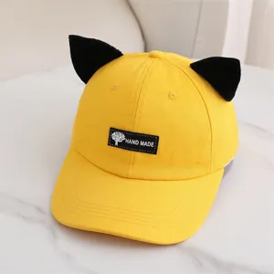 Gorra de béisbol amarilla con lindas orejas de gato negras y etiqueta frontal de detalle.