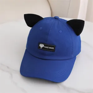 Primer plano detallado de la elegante gorra de béisbol azul con orejas de gato negras y etiqueta.