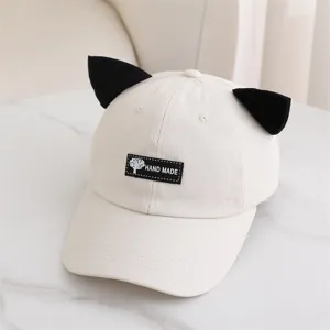 Primer plano de bonita gorra de béisbol beige con orejas de gato y parche negro.
