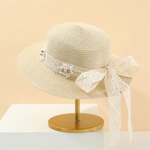 Nahaufnahme des eleganten Strohhutes mit zarter Spitzenbandschleife und schönen floralen Details.