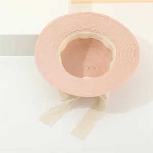 Detailaufnahme eines rosa Strohhutes mit beiger Schleife, eleganter Sommersonnenschutz.