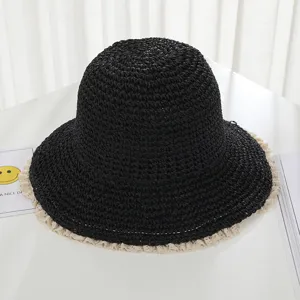 Detailed shot of black woven straw bucket hat with delicate beige lace trim for summer beach.