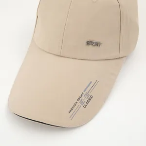 Detailed view of khaki baseball cap featuring metal sport logo and brim graphic print.