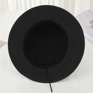 Vue détaillée d'un chapeau de paille noir à bord plat, idéal pour la protection solaire.