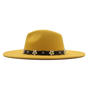 Nahaufnahme des gelben Wollfilz-Fedora-Hutes mit schwarzem Ledergürtel und weißen Blumen-Nieten.