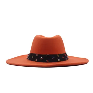 Detailansicht des orangefarbenen Wollfilzhutes mit bunten Strasssteinen am schwarzen Band.
