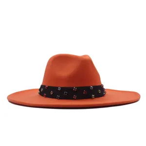 Detailansicht des orangefarbenen Filzhutes mit schwarzem Band und bunten Strasssteinen.