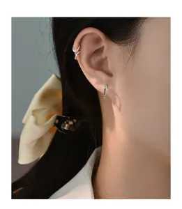 Nahaufnahme von Sterling Silber Ohrklemme und kleinen Creolen am Ohr, minimalistischer Stil.