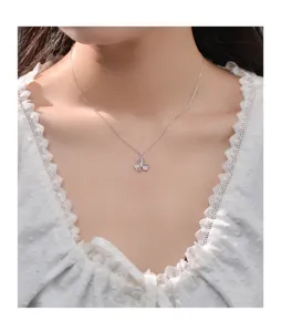 Close-up detail view of a delicate silver three-leaf clover pendant necklace on a model.
