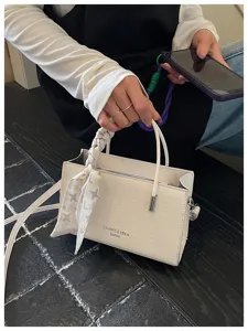 Detail view of white mini crossbody bag with chic scarf decoration and elegant texture style.