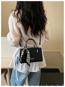 Detail shot of a black crossbody shoulder bag featuring a stylish houndscoot scarf and strap.