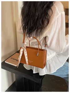 Brown croc-embossed shoulder bag detail view with stylish scarf handle and modern design.