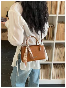 Detailed view of trendy brown crocodile pattern women shoulder bag with stylish scarf.