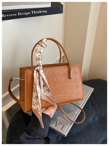 Detailed view of the brown crocodile pattern handbag handle wrapped with elegant silk scarf.