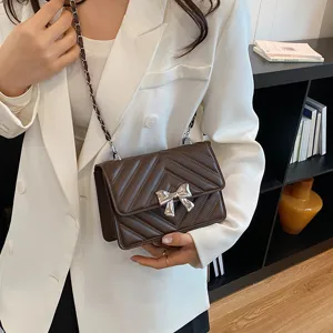 Stylish brown quilted crossbody bag with chic silver bow and chain strap for women daily.