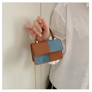 Close-up detail of the mini color-block denim and leather shoulder bag with gold chain.