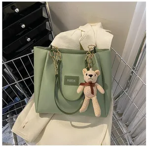 Detailed view of a stylish green PU leather tote bag with chain strap and cute bear keychain.