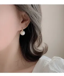 Detailaufnahme einer eleganten Einzelperle mit goldener Hakenbefestigung am Ohrläppchen.