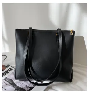 Close-up view of a black minimalist leather tote bag for women with dual straps and zipper closure.
