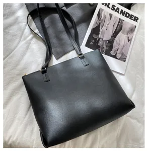 Black PU leather tote bag detail, minimalist single shoulder design with gold tone metal rings.