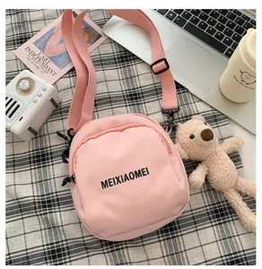 Cute pink canvas crossbody bag detail shot with adjustable strap and chic letter print.
