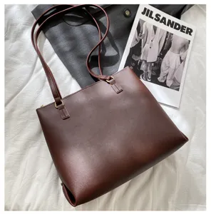 Detail of dark brown leather tote bag, highlighting smooth texture and gold metal rings.