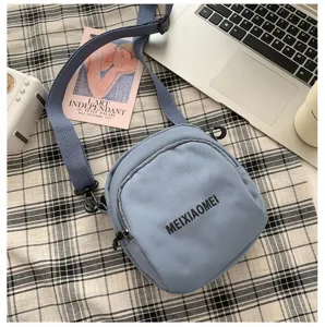 Detailed view of the trendy blue canvas crossbody bag featuring letter print and adjustable strap.