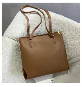 Detail view of the brown women's tote bag showing textured surface and metal zipper pull.