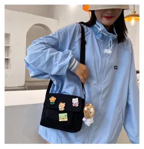 Black canvas crossbody bag for women, cute Harajuku style messenger bag with pins and plush.