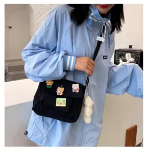 Cute Japanese Harajuku black canvas crossbody bag with cartoon pins and fluffy bear pendant.