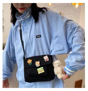Detailed shot of cute canvas crossbody bag with bear pendant and cartoon badges.