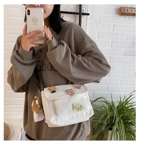 Detailed view of the cute Japanese harajuku white canvas messenger bag with adorable pins and plush.