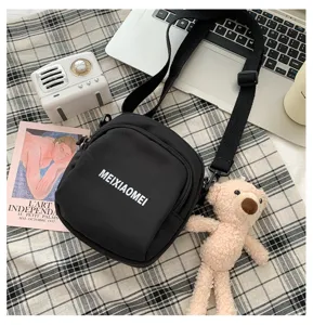 Korean style canvas crossbody bag for women with cute bear pendant and adjustable strap.