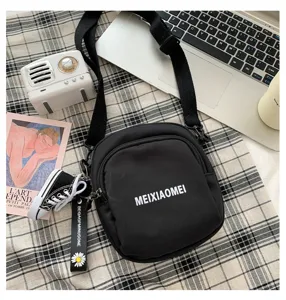 Black canvas crossbody bag with front zipper pocket and trendy mini shoe keychain pendant.