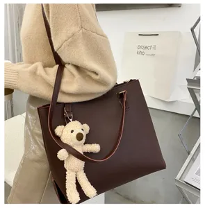 Stylish women brown PU leather tote bag with cute bear pendant, large capacity daily shoulder bag.
