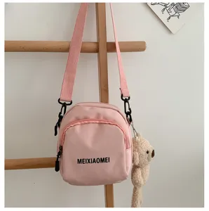 Pink canvas crossbody bag detail shot featuring cute teddy bear pendant and zipper pocket.