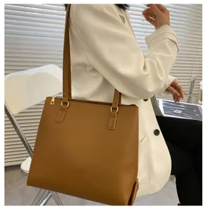 Detail view of a stylish brown leather tote bag showcasing shoulder straps and golden hardware.