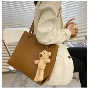 Stylish brown leather tote bag with cute bear pendant, large capacity for daily use.
