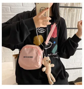 Detailed shot of the pink canvas crossbody bag with cute bear charm and shoulder strap.