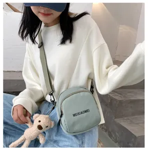 Detailed view of casual canvas crossbody bag with cute bear pendant, stylish daily wear.