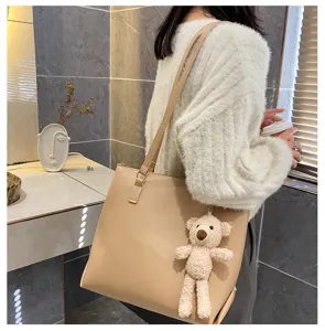 Beige PU leather tote bag with cute bear pendant, stylish women shoulder bag for daily use.