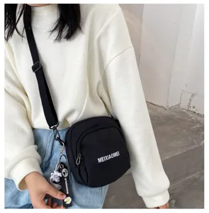 Black canvas crossbody bag for women, casual shoulder bag with front pocket and charms.