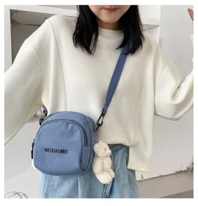 Detail view of the stylish casual crossbody canvas bag with cute bear pendant and strap.