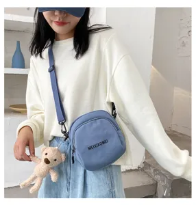 Casual canvas crossbody bag for women with cute bear pendant and blue shoulder strap.