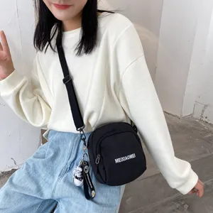 Casual black canvas crossbody bag for women, stylish daily shoulder bag with cute keychain.