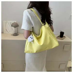 Vue détaillée d'un élégant sac cabas jaune en cuir souple avec un charmant pendentif en peluche.
