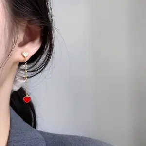 Elegante lange Quasten-Herz-Ohrringe für Damen mit funkelndem Stein und rotem Anhänger.