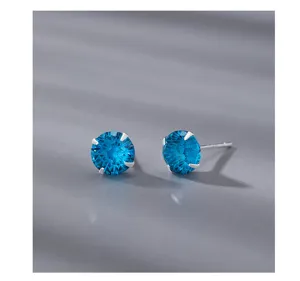 Boucles d'oreilles puces en zircone bleue gros plan, bijoux en argent minimalistes.