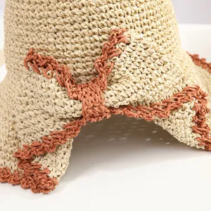 Gros plan détail du chapeau de paille tissé d'été pour femmes, nœud marron contrasté texturé.